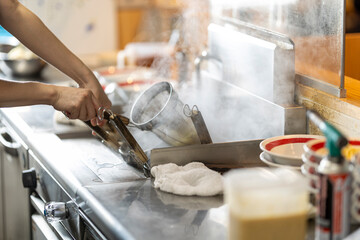 Chef Preparing Ramen in Japanese Noodle Shop with Steam Rising