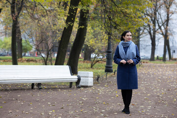 Fototapeta premium Mature woman walking on city sidewalk during autumn near residential architecture.