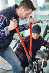 man using bolt croppers on a bicycle