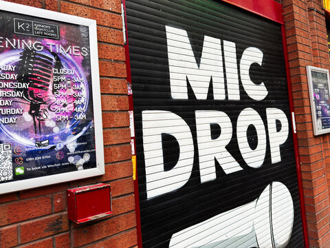 Urban Karaoke Nightclub storefront with mic drop lettering on a black shutter in Manchester, UK