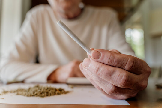 Close-up of senior man holding marijuana joint at home