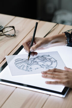 Woman's hand drawing template on light table