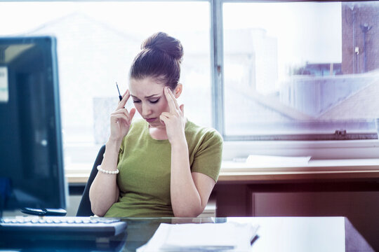 Frustrated female entrepreneur with head in hands in board room at office
