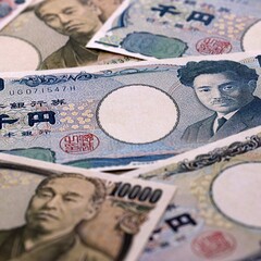 Japanese yen money bills pile on table. Japan banknotes of JPY currency close up. © Larysa