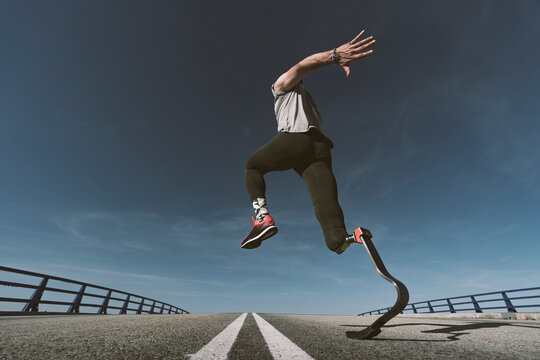 Disabled athlete with leg prosthesis exercising on a road
