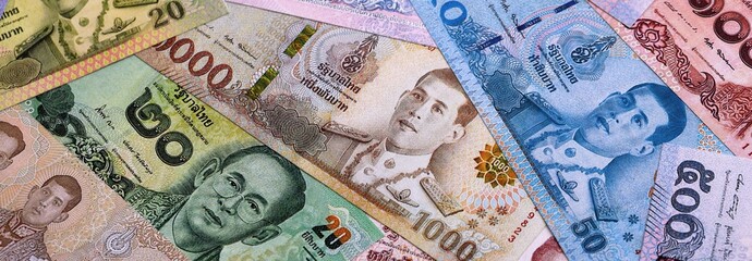Obraz premium Thai baht money bills pile on table. Thailand banknotes of THB currency close up.