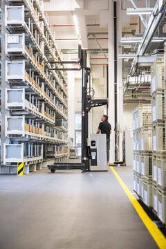 Worker operating forklift in factory warehouse