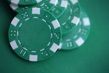 Green casino poker chips on green gaming table close up. Few amount of green casino chips