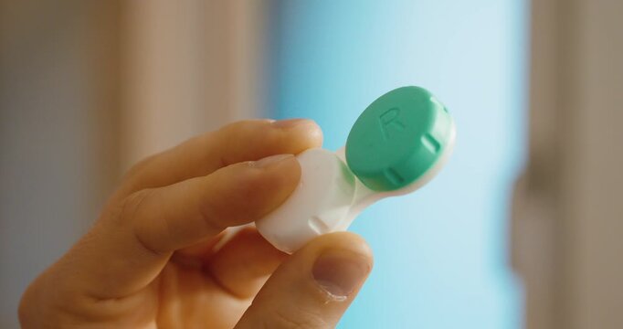 contact lens case held in hand. Concept of correct contact lens storage, hygiene routine, cleaning, eye care and safe handling to prevent infections.
