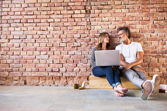 Businessman and woman sitting in a loft, using laptop, founding a start-up company