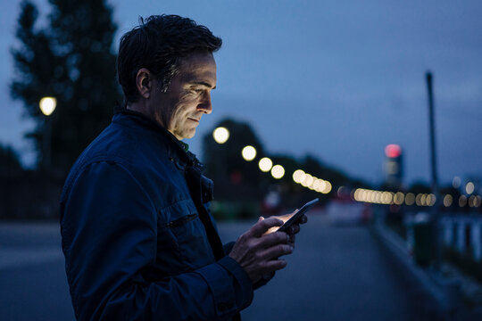 Mature man using tablet on a promenade at dusk