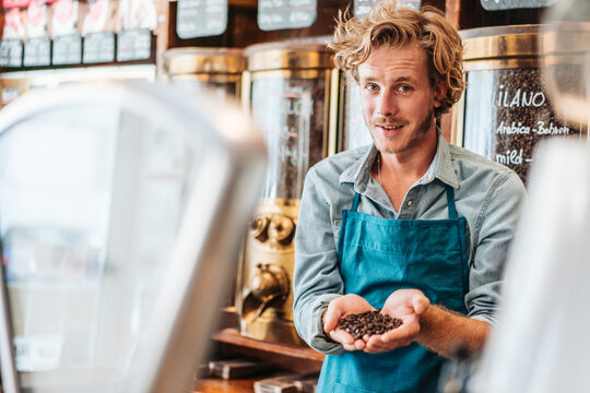 Portrait of coffee roaster in his shop holding coffee beans