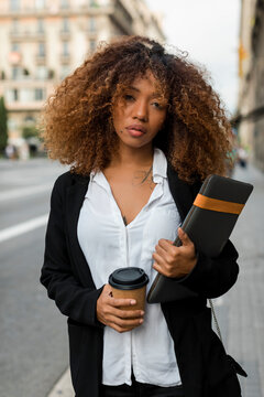 Young woman with laptop bag and coffee to go in the city, missing the taxi
