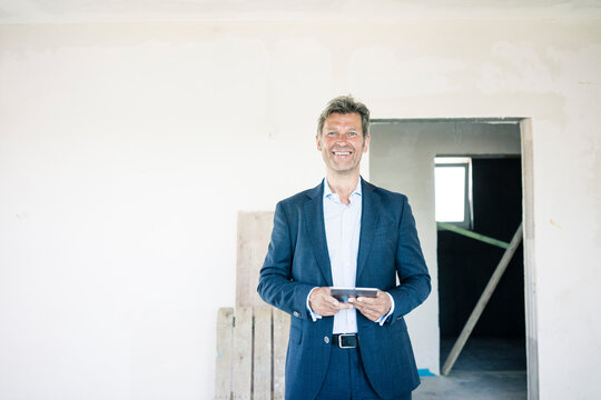 Portrait of smiling man in suit in building under construction