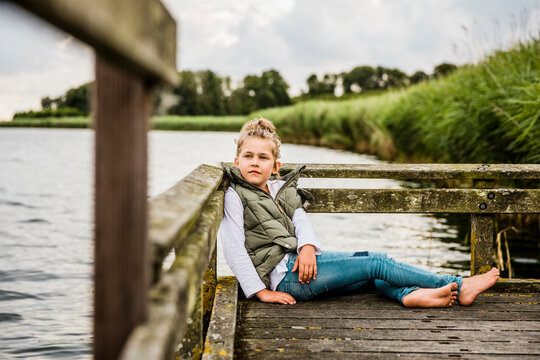 Girl sitting on jetty at a lake