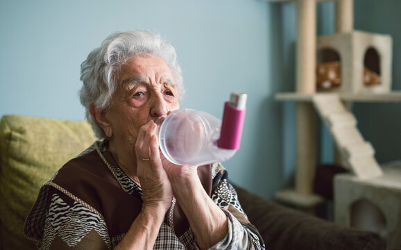 Senior woman using inhaler at home