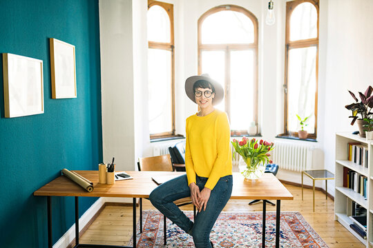 Portrait of smiling businesswoman in home office sitting on table