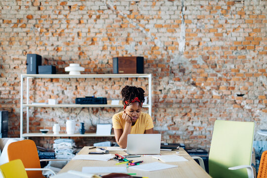 Young woman sitting at table using laptop