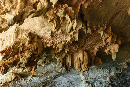 Intricate limestone formations and mineral deposits cover the ceiling of Konglor Cave in central Laos. The rugged textures and layered rock surfaces display a variety of natural patterns shaped by