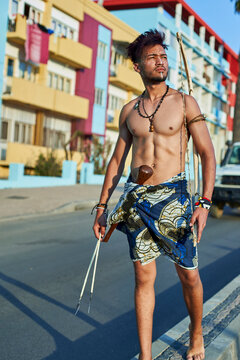 Tribal man with his traditional arch and arrows in the middle of the city with cars passing by, Lubango, Angola