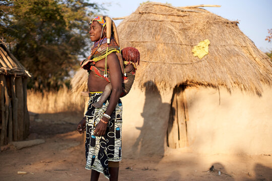 Muhila tribe woman carrying her child on her back, Kehamba, Chibia, Angola