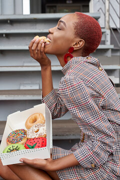 Young woman eating a doughnut from the box