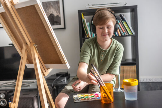 Boy painting at easel and listening to music