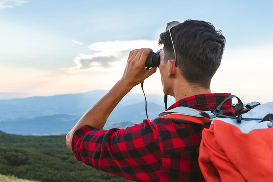 Italy, Monte Nerone, hiker in the mountains looking with binocular