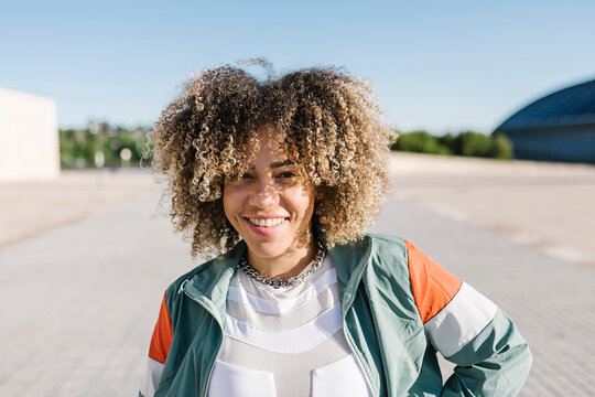 Confident young woman with curly hair during sunny day