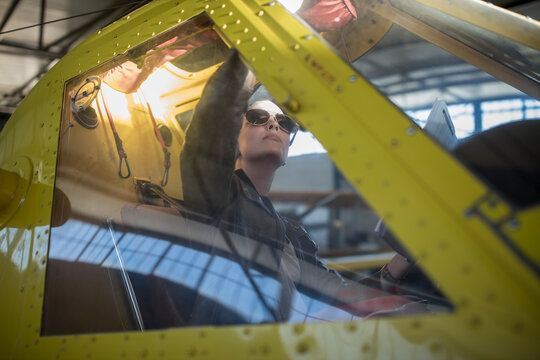 Female pilot inspecting light aircraft cockpit