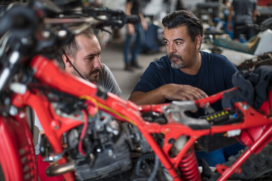 Two mechanics working on motorcycle in workshop together