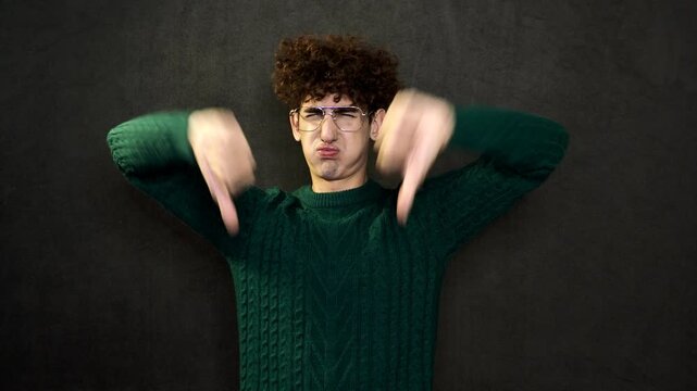 The man grimaces and points with his hands and finger.