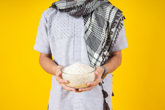 Closeup of Asian Male Holding Rice for Zakat to Donate During Ramadan Isolated on Yellow Isolated