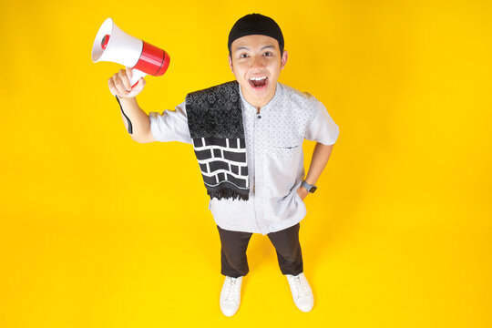 Top View of Young Muslim Man Shouting Using Megaphone Isolated on Yellow Background