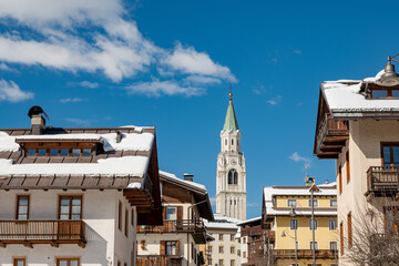 Sunny Winter View of Cortina d'Ampezzo with Snow Covered Rooftops and Dolomites Mountains, Italy