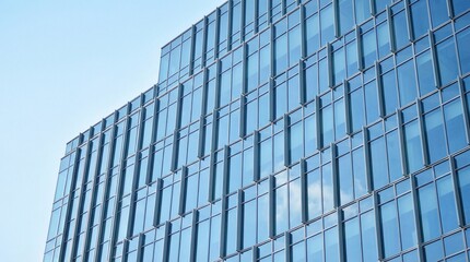 Fototapeta premium Modern architectural design of a glass facade building with geometric patterns against a clear blue sky