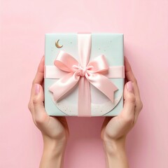 Delicate Pale Blue Gift Box Wrapped in Soft Pink Ribbon Held by Gentle Hands Against a Pastel Pink Background