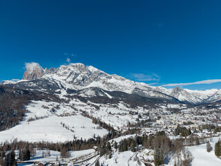 Sunny Winter Aerial Panorama of Cortina d'Ampezzo with Snowy Tofane Mountains, Dolomites, Italy