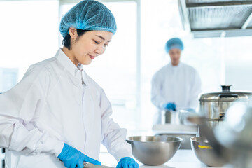 厨房で料理する衛生白衣を着た女性調理師　給食センター　給食室 © metamorworks