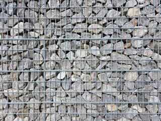 Gabion wall, a functional and modern architectural feature used for landscaping, erosion control, or decorative fencing, galvanized steel wire mesh grid,natural grey crushed stones.