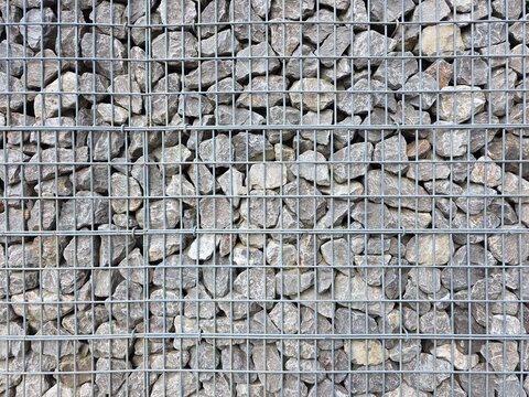 Gabion wall, a functional and modern architectural feature used for landscaping, erosion control, or decorative fencing, galvanized steel wire mesh grid,natural grey crushed stones.
