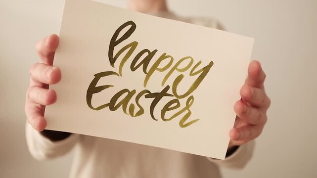 Hand-painted watercolor "Happy Easter" calligraphy lettering. Artistic process or finished greeting on white textured paper, featuring spring pastel green color. Ideal for holiday greetings, seasonal 