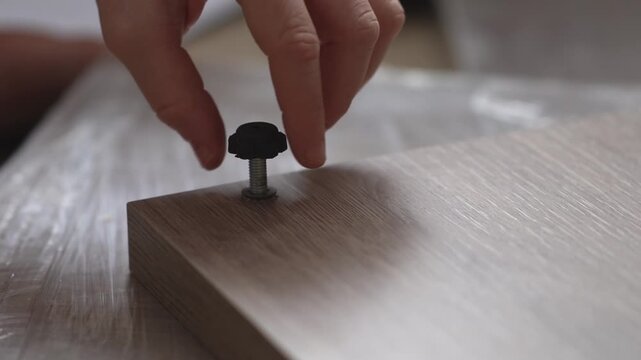Furniture assembly. Teenager's crop hand screws furniture leg into furniture