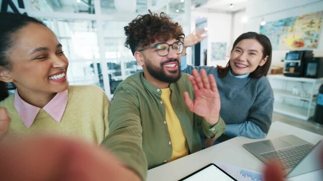 Cheerful office team taking selfie at workplace. Group colleagues extending arm and holding camera. Business people waving hands and smiling. Friendly workers greeting viewer in creative studio.