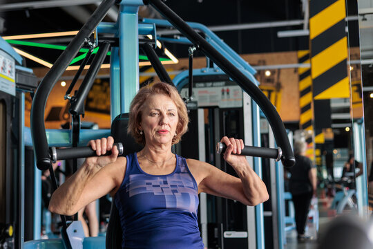 Active Senior Woman Using Chest Press Machine in Gym, Strength Training After 60, Healthy Aging, Maintaining Muscle Tone, Mobility and Independent Lifestyle. Copy space