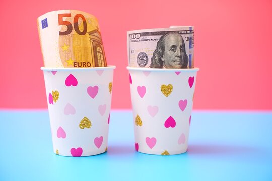 Euro and US dollar banknotes in paper cups on colorful background