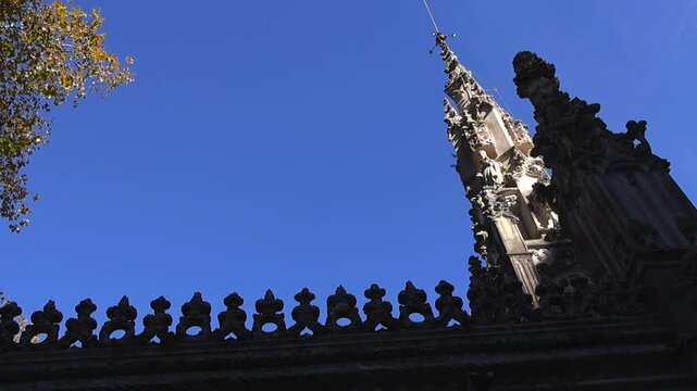 Upward view of ornate historic tower and decorative stonework against clear blue sky