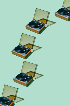 Retro vinyl record players arranged diagonally on pastel studio background