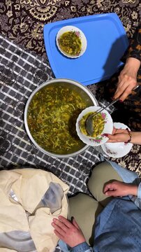 serving Persian delicious ash herb noodle soup in traditional gathering Nowruz cozy home dry mint garlic caramelized onion beans bowl hot family clay spinach Iran rural peaceful Kurdish cooked dinner