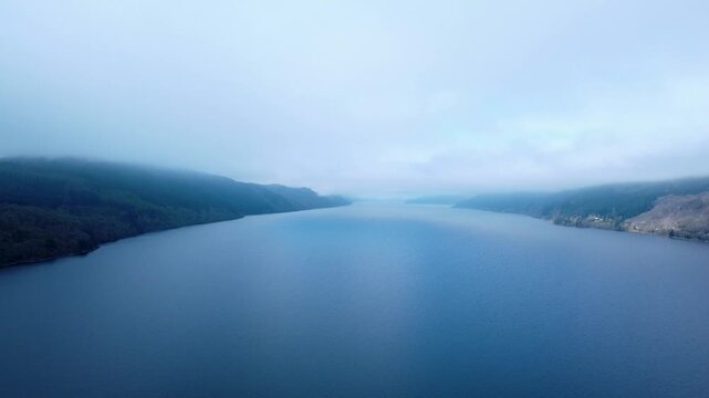 A high aerial view across a misty Lough Ness, slowly tracking right. Taken early in the morning before the mist has dispersed.